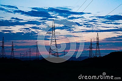 Power lines against dark sunset sky Stock Photo