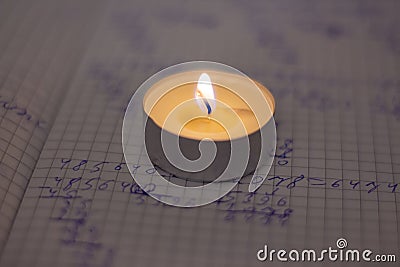 Power outage. Home school assignments are about candles. Elementary school math problems and a candle. Stock Photo