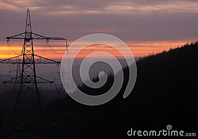 Power Pylons run through a forest at Sunset in the UK, Peak District Stock Photo