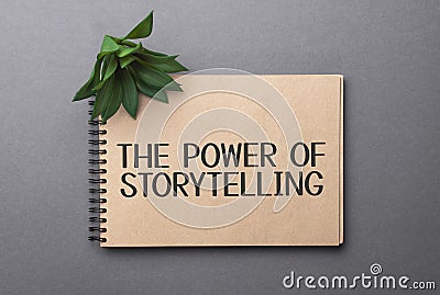 THE POWER OF STORYTELLING text on craft colored notepad and green plant on the dark background Stock Photo