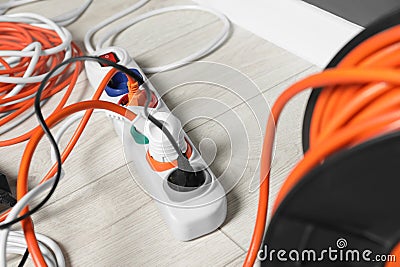 Power strip with different electrical plugs on white laminated floor, closeup Stock Photo