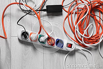 Power strip with different electrical plugs on white laminated floor, flat lay Stock Photo