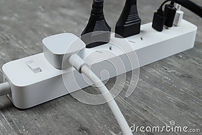 Power strip with multiple electrical cords plugged in on gray background Stock Photo