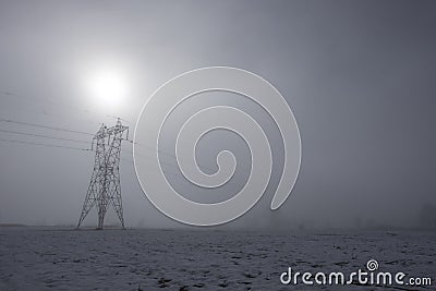 Power tower current distribution lines, in winter snowy countryside in a misty atmosphere Stock Photo