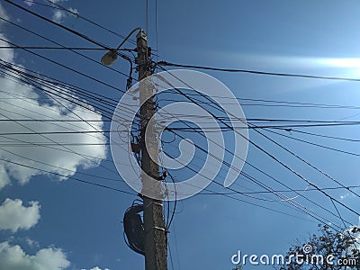 Power wires on a pillar against a blue sky Stock Photo