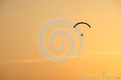 Powered paraglider flying away with sunrise Stock Photo