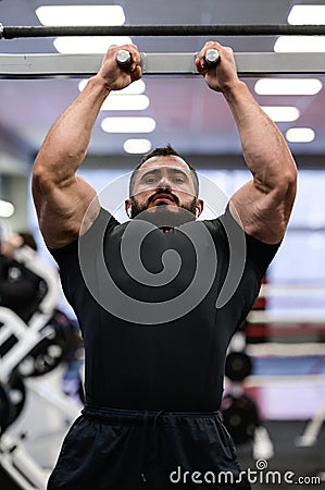 Powerful active strong caucasian man with beard making chin ups on crossbar in athletic sport gym Stock Photo