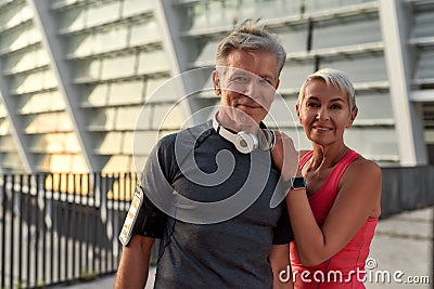 Powerful couple. Portrait of happy middle-aged man and woman in sport clothing looking at camera with smile while Stock Photo