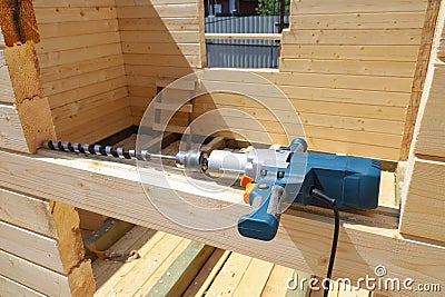 Powerful drill for drilling dowel holes, building wooden farmhouse Stock Photo