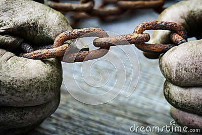 Powerful male hands trying to tear an old rusty chain Stock Photo