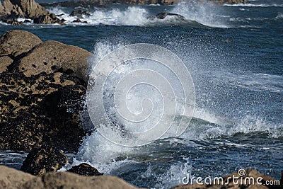 Powerful ocean waves crashing against rocks on the shore Stock Photo