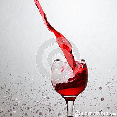 Powerful splash of red wine in a glass on a gray background Stock Photo