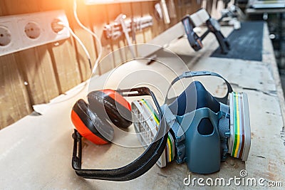 PPE respirator face half mask and ear protection equipment on wooden workbench of carpentry professional woodwork workshop. Worker Stock Photo