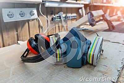 PPE respirator face half mask and ear protection equipment on wooden workbench of carpentry professional woodwork workshop. Worker Stock Photo