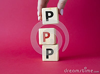 PPP private public partnership symbol. Wooden cubes with words PPP. Businessman hand. Beautiful red background. Business and PPP Stock Photo