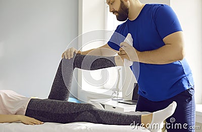Pprofessional male masseur therapist kneads female patient& x27;s leg in physiotherapy clinic. Stock Photo