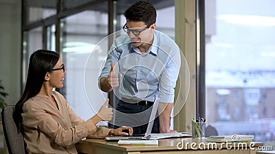 PR agency colleagues showing thumbs up looking each other, satisfied with result Stock Photo