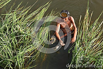 Fisherman pulls a fish out of harpoon in marsh Editorial Stock Photo