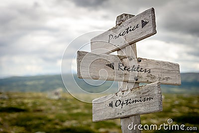 Practice reckless optimism ext on wooden signpost outdoors in nature. to illustrate the importance of staying positive during glob Stock Photo