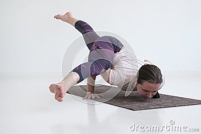 Practicing yoga, doing Eka Pada Koundinyasana 2, arm balance twisted pose. Stock Photo