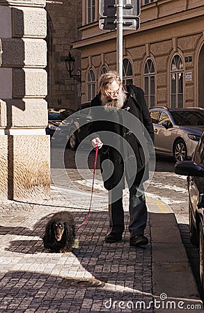 an old man with a dog on the tourist streets of Prague Editorial Stock Photo