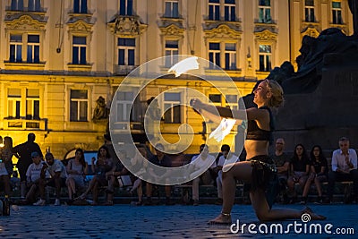 Prague, Czech Republic - July 22, 2019: Female fire dancer juggles with sticks on street of old town square in Prague. Fire show. Editorial Stock Photo