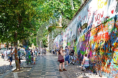 Prague, Czech Republic - June 27 2019: Tourists taking photos in front of famous John Lennon Wall in the center of Czech capital. Editorial Stock Photo