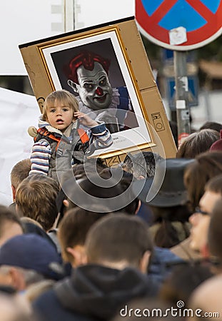 A child in front of the caricature of Milos Zeman shown as an evil clown at the demonstration on Prague Wenceslas square Editorial Stock Photo