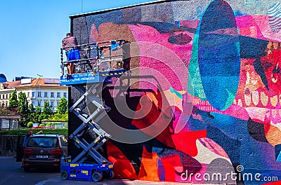 Worker painting building wall in bright colors Editorial Stock Photo