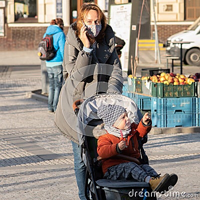 11/16/2020. Prague, Czech Republic. A mother is crossing the street with her small child in a baby carriage close to Hradcanska Editorial Stock Photo