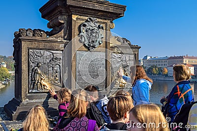 PRAGUE, CZECH REPUBLIC - OKTOBER 10, 2018: Tourists rub metal statue as a tradition for wishing on a bridge in Prague Editorial Stock Photo