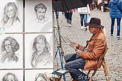 Prague, Czech Republic - September 27, 2014: Street portrait painter and examples of his art drawn with pencil. Editorial Stock Photo
