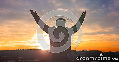 Praise and worship concept: Silhouette human raising hands to praying God on blurred cross with crown of throne sunset background Stock Photo