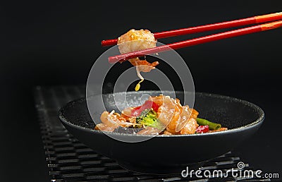 Prawn in red chopsticks on black background Stock Photo