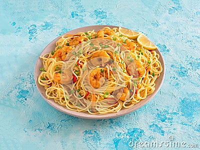 Prawn Schezwan Noodles with vegetables in a plate on a blue table Stock Photo