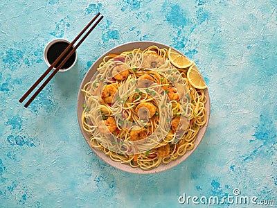 Prawn Schezwan Noodles with vegetables in a plate on a blue table. Top view Stock Photo