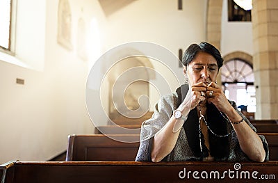 Pray, church and senior woman praying with a rosary in a calm, zen chapel alone, holy and spiritual. Prayer, worship and Stock Photo