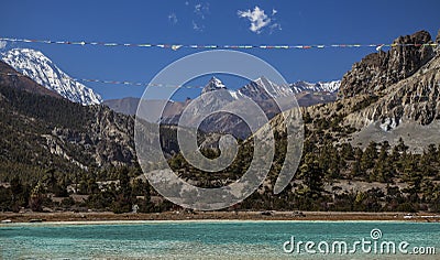 Prayer flags over mountain lake in Annapurna Circuit trail, Nepal. Stock Photo