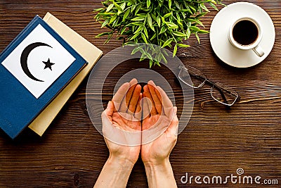 Praying concept with hands, Koran Islam holy book, crescent and star on wooden table top view Stock Photo