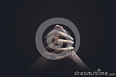 Praying hands with faith in religion and belief in God on dark background. Power of hope or love and devotion Stock Photo