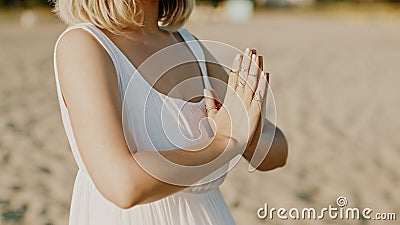Praying meditating woman, reading mantras, directs thoughts, requests or gratitude to universe. Beach, morning near sea Stock Photo