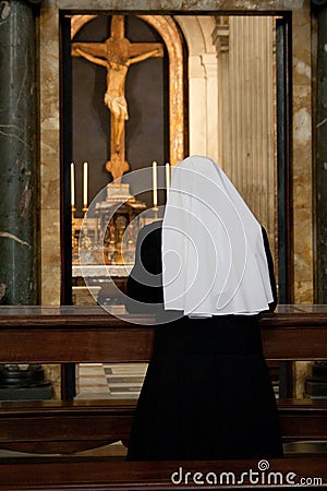 Praying nun in a temple of Vatican opposite the statue of Jesus Christ Stock Photo