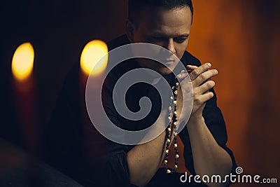 Praying priest. Portrait of priest Next to the candles prays Stock Photo