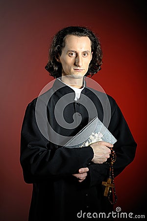 Praying priest with wooden cross and Holy Bible Stock Photo