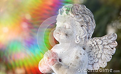 Praying stone angel with colorful sunbeam Stock Photo