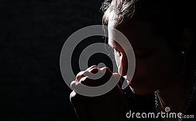 Praying young Woman portrait on dark Stock Photo