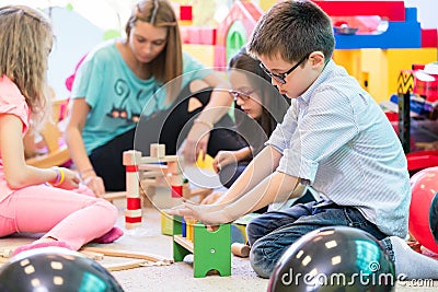 Pre-school boy cooperating with kids under guidance of kindergarten teacher Stock Photo