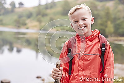A pre-teen boy standing on the shore of a lake, looking to camera, front view, waist up, Lake District, UK Stock Photo