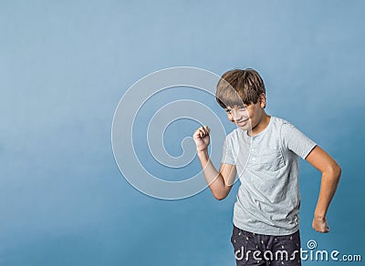 A pre-teen tween boy being silly on a colorful blue background with copy space Stock Photo