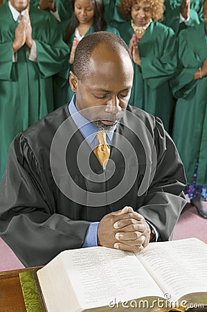 Preacher by altar in church Bowing Head in Prayer Stock Photo